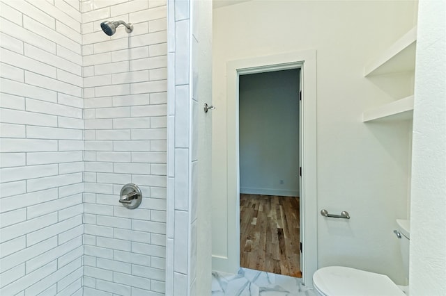 bathroom with a tile shower, toilet, and hardwood / wood-style flooring