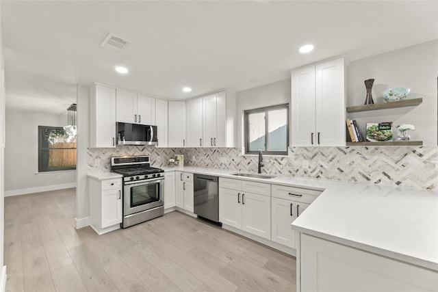 kitchen with stainless steel appliances, white cabinetry, light hardwood / wood-style floors, and sink