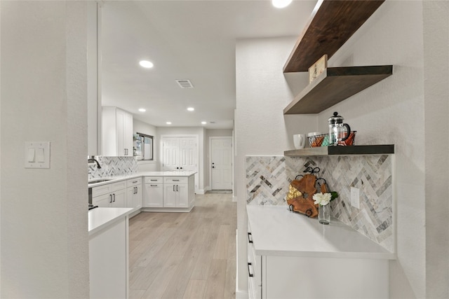 kitchen with backsplash, sink, white cabinets, and light hardwood / wood-style floors