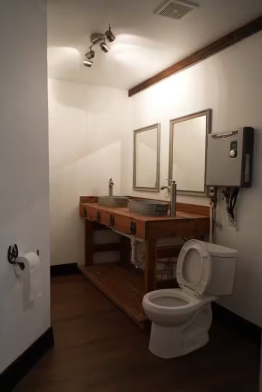 bathroom with hardwood / wood-style floors, tankless water heater, toilet, and sink