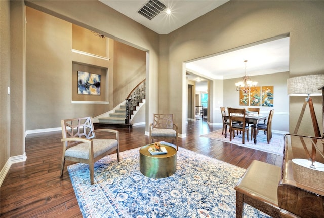 living room featuring an inviting chandelier, dark hardwood / wood-style floors, and ornamental molding