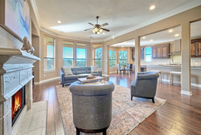 living room featuring hardwood / wood-style floors, ceiling fan, crown molding, and sink