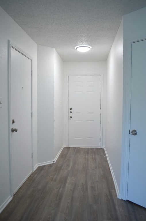 hallway featuring a textured ceiling and dark hardwood / wood-style floors