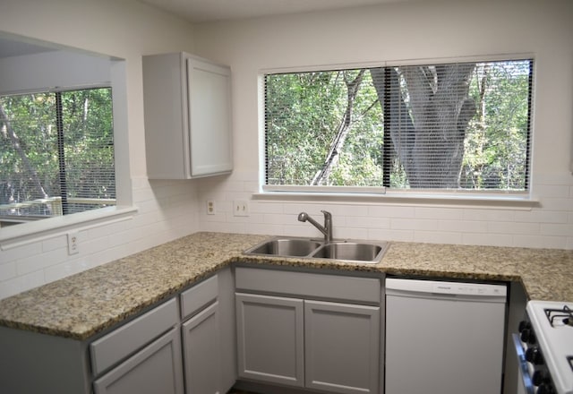 kitchen with white appliances, backsplash, plenty of natural light, and sink