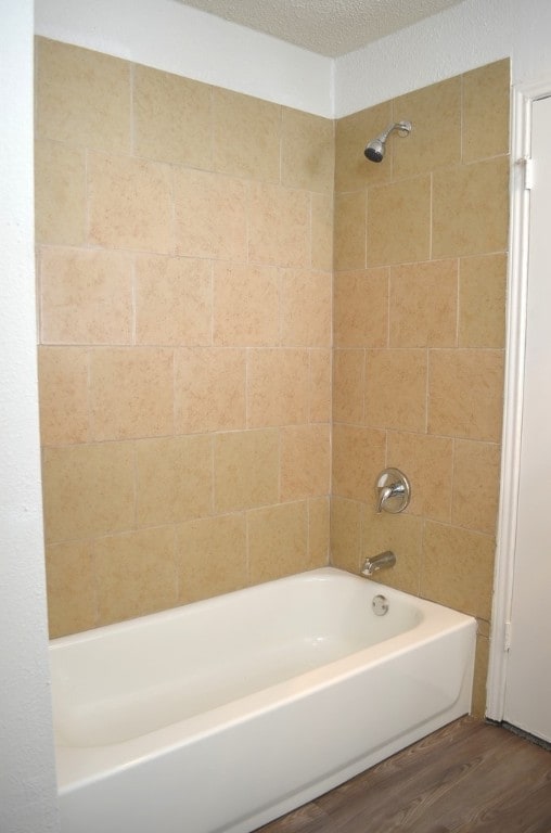 bathroom featuring hardwood / wood-style floors, a textured ceiling, and tiled shower / bath