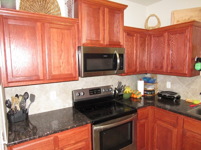 kitchen featuring decorative backsplash, sink, dark stone counters, and appliances with stainless steel finishes