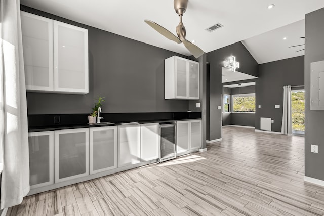 kitchen featuring ceiling fan, white cabinets, beverage cooler, and lofted ceiling