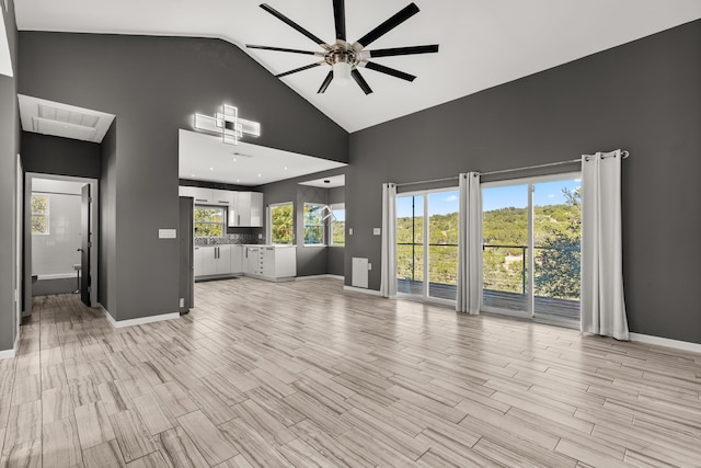 unfurnished living room featuring ceiling fan, a healthy amount of sunlight, and high vaulted ceiling