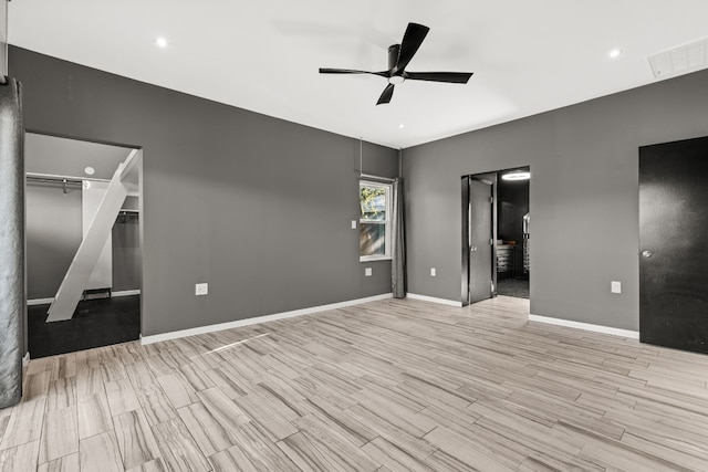 unfurnished bedroom featuring ceiling fan, a closet, light hardwood / wood-style floors, and a spacious closet