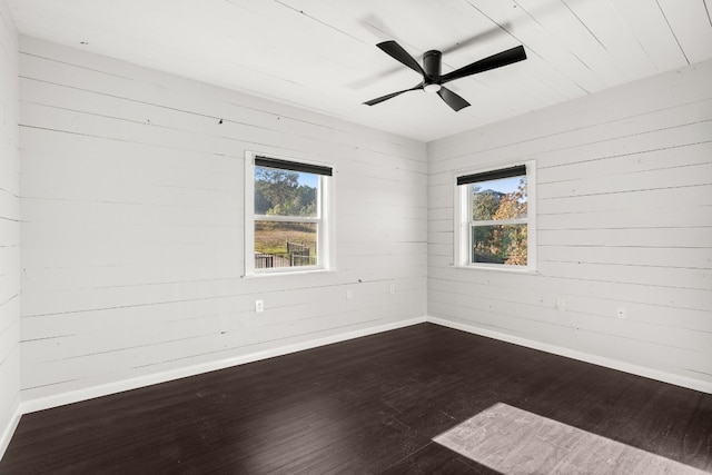 spare room featuring ceiling fan, wood walls, and wood-type flooring