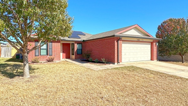 single story home with solar panels, a garage, and a front yard