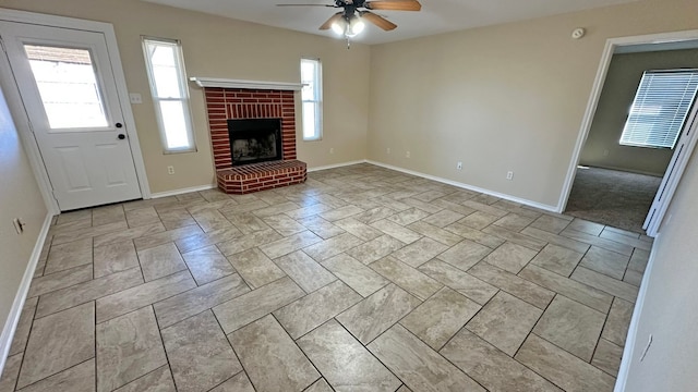 unfurnished living room with a brick fireplace and ceiling fan