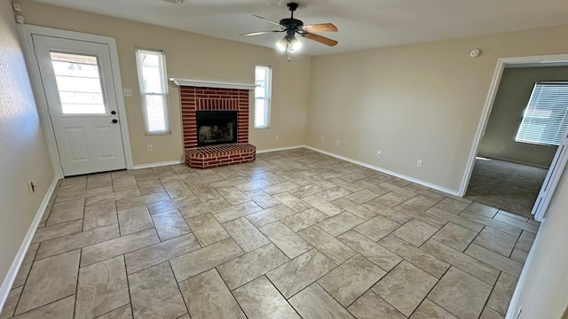 unfurnished living room featuring ceiling fan and a brick fireplace