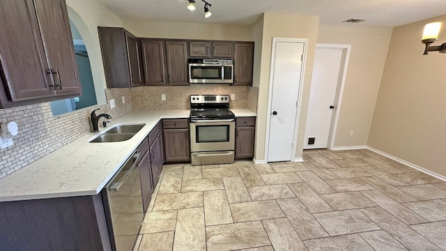 kitchen with decorative backsplash, sink, dark brown cabinets, and stainless steel appliances