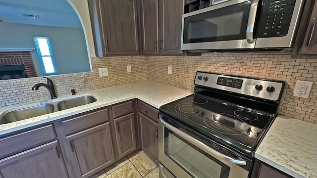 kitchen featuring dark brown cabinetry, sink, appliances with stainless steel finishes, and tasteful backsplash