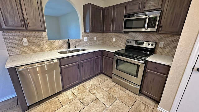 kitchen featuring backsplash, dark brown cabinetry, sink, and appliances with stainless steel finishes