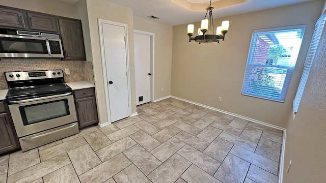 kitchen with dark brown cabinets, hanging light fixtures, appliances with stainless steel finishes, and an inviting chandelier