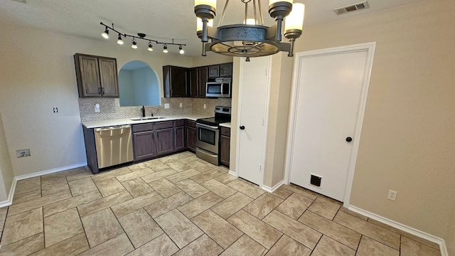 kitchen featuring dark brown cabinetry, sink, stainless steel appliances, tasteful backsplash, and pendant lighting