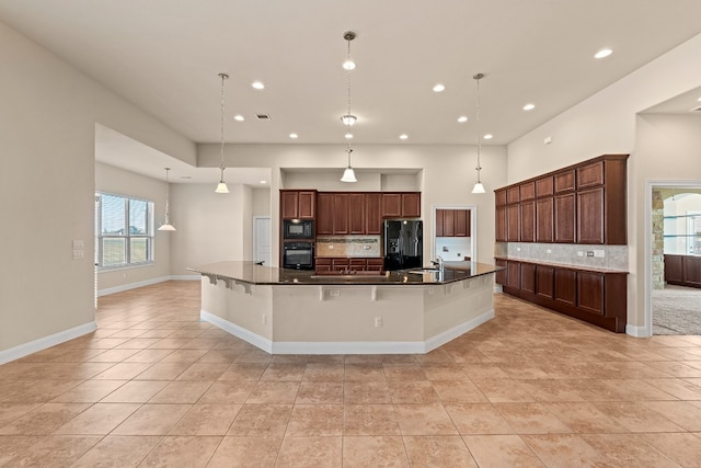 kitchen featuring a large island, backsplash, decorative light fixtures, a kitchen bar, and black appliances