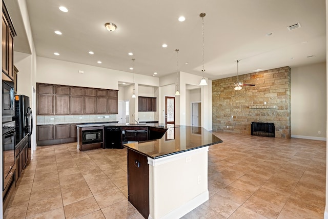 kitchen featuring a center island, backsplash, black appliances, a stone fireplace, and ceiling fan