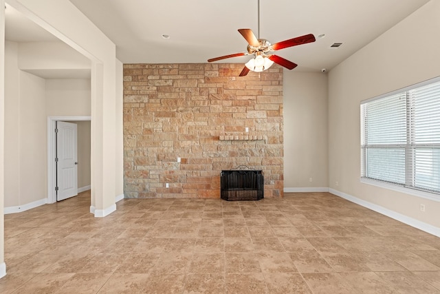 unfurnished living room with a stone fireplace and ceiling fan