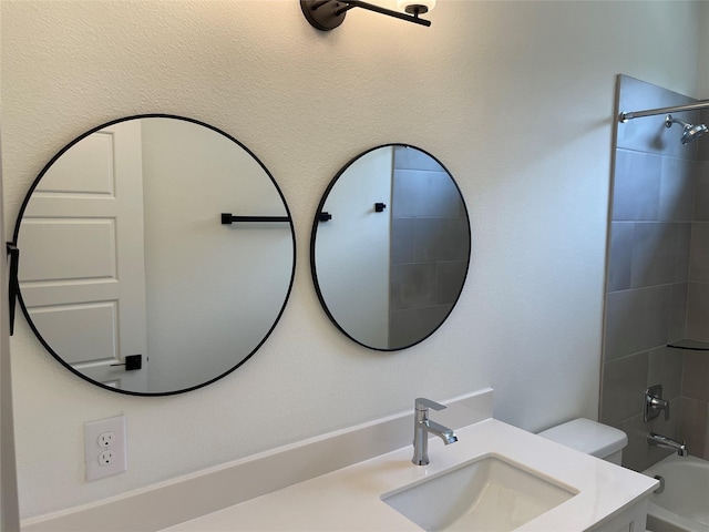 full bathroom with toilet, tiled shower / bath, and vanity