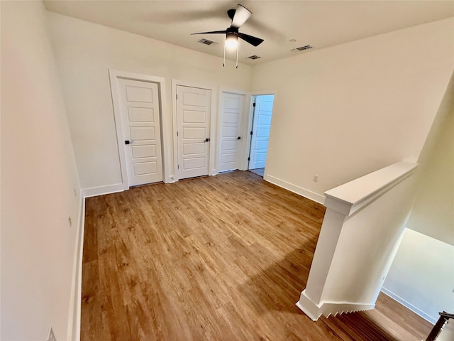 unfurnished bedroom with ceiling fan, two closets, and hardwood / wood-style flooring