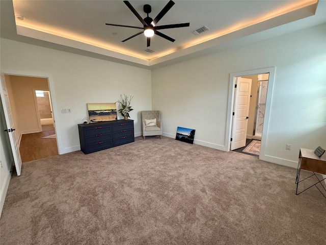 carpeted bedroom featuring ceiling fan, connected bathroom, and a tray ceiling