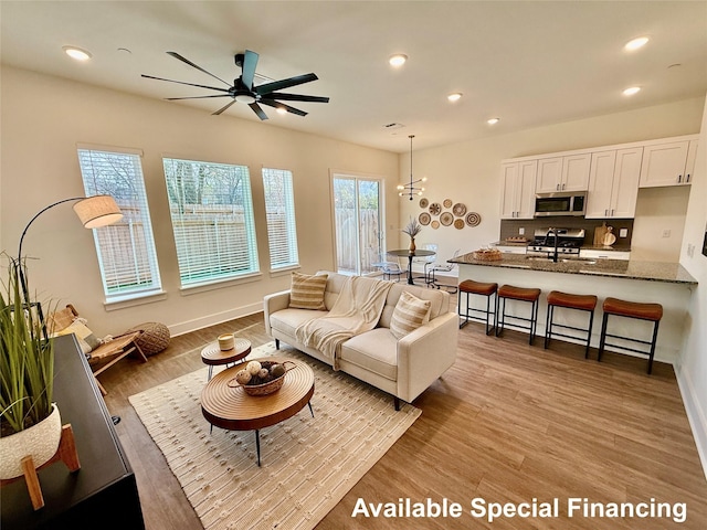 living room with ceiling fan, sink, and light hardwood / wood-style flooring