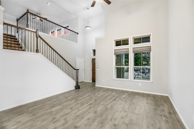 entryway with ceiling fan, a towering ceiling, and light hardwood / wood-style flooring