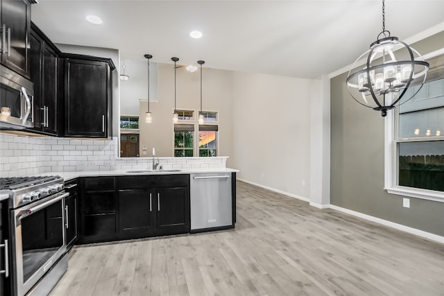 kitchen featuring sink, stainless steel appliances, decorative light fixtures, and light hardwood / wood-style floors