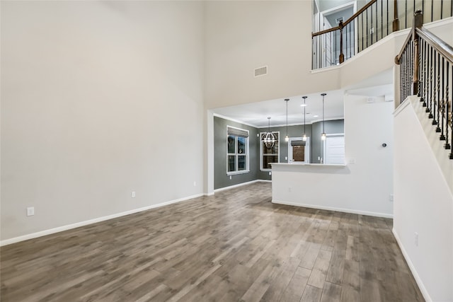 unfurnished living room featuring wood-type flooring and a high ceiling