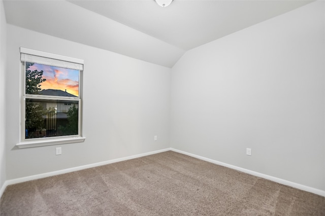 carpeted empty room with vaulted ceiling