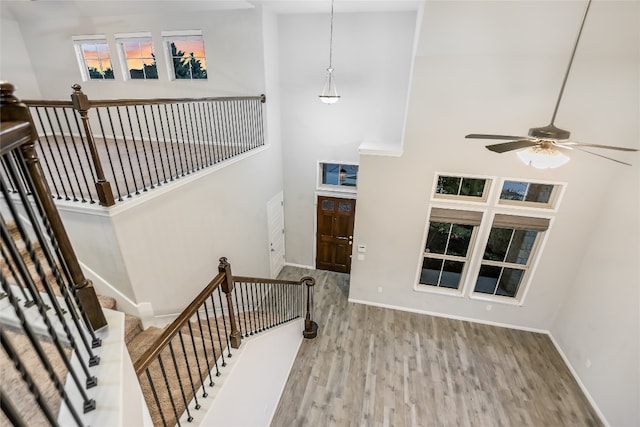 stairs with a high ceiling, hardwood / wood-style flooring, and ceiling fan