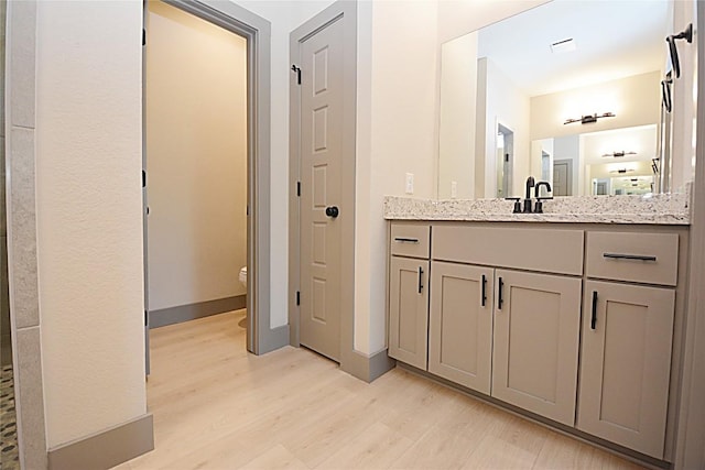 bathroom featuring hardwood / wood-style flooring, vanity, and toilet