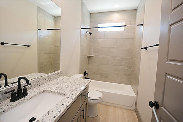 full bathroom with vanity, hardwood / wood-style flooring, toilet, and tiled shower / bath combo