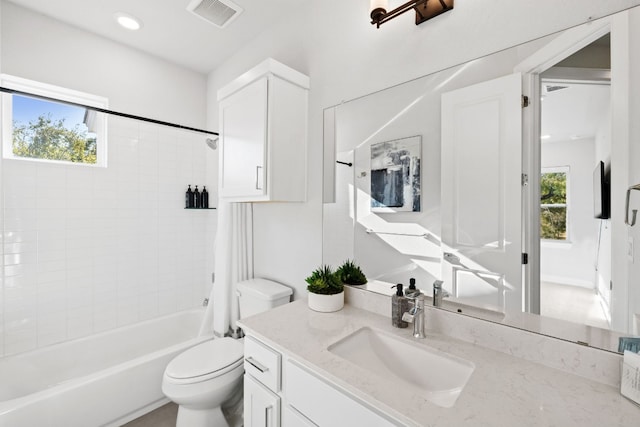 full bathroom with vanity, a healthy amount of sunlight, tiled shower / bath combo, and toilet