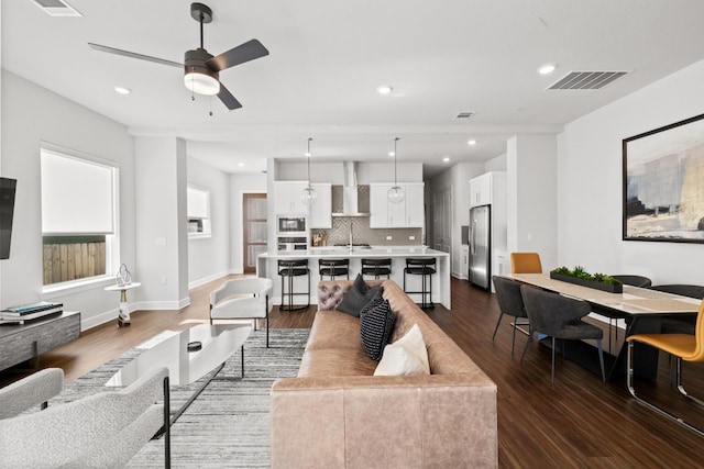 living room with ceiling fan and dark hardwood / wood-style flooring