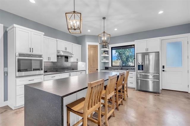 kitchen featuring pendant lighting, a kitchen breakfast bar, a kitchen island, white cabinetry, and stainless steel appliances