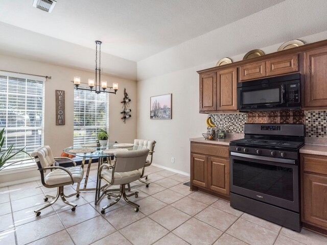 kitchen with a notable chandelier, gas stove, light tile patterned floors, and backsplash