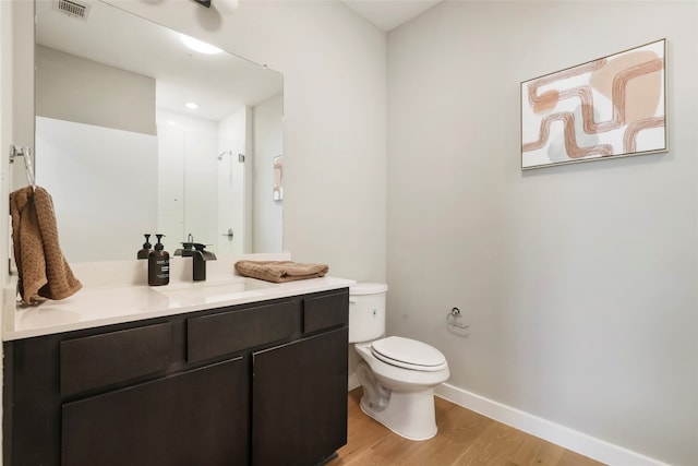 bathroom featuring a shower, vanity, wood-type flooring, and toilet