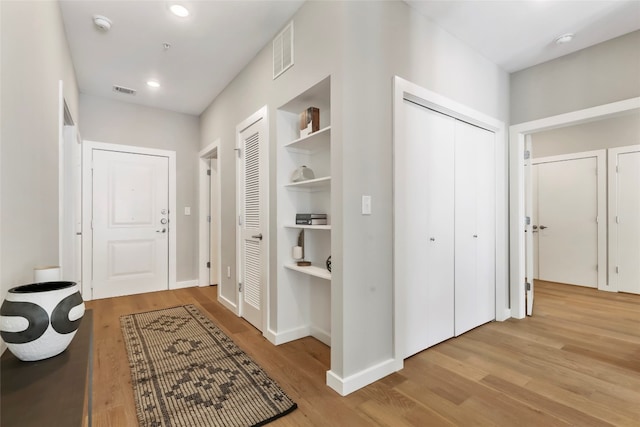 corridor featuring built in shelves and light hardwood / wood-style flooring