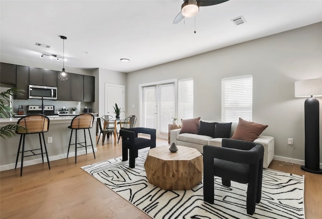 living room with ceiling fan and light hardwood / wood-style flooring