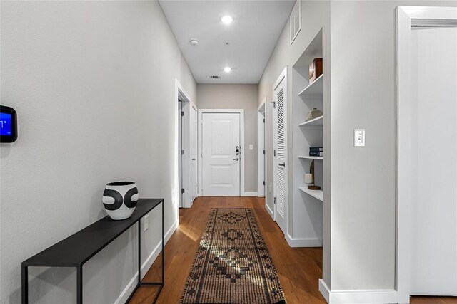 corridor featuring dark wood-style flooring, baseboards, and recessed lighting