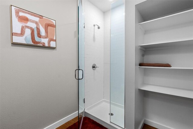 full bathroom with baseboards, a stall shower, and wood finished floors