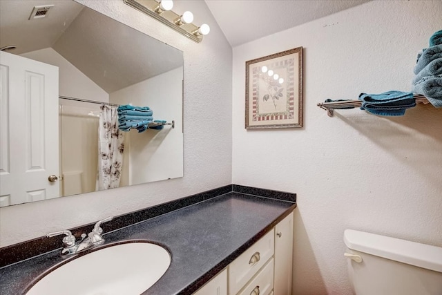 bathroom with toilet, vanity, vaulted ceiling, and curtained shower