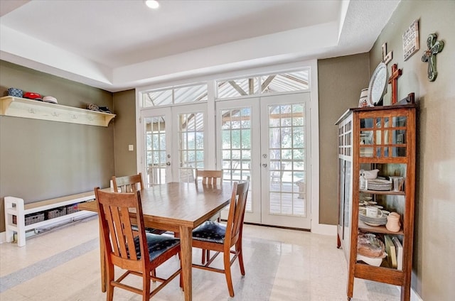 dining area with a tray ceiling and french doors