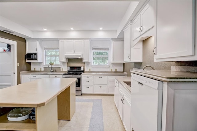 kitchen with white cabinets, a wealth of natural light, a kitchen island, and appliances with stainless steel finishes