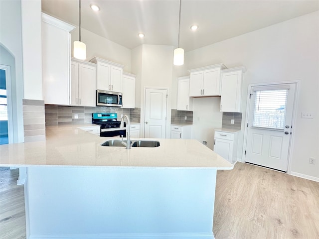 kitchen with black range oven, sink, hanging light fixtures, light hardwood / wood-style floors, and white cabinetry