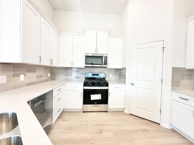 kitchen featuring tasteful backsplash, white cabinetry, light wood-type flooring, and appliances with stainless steel finishes